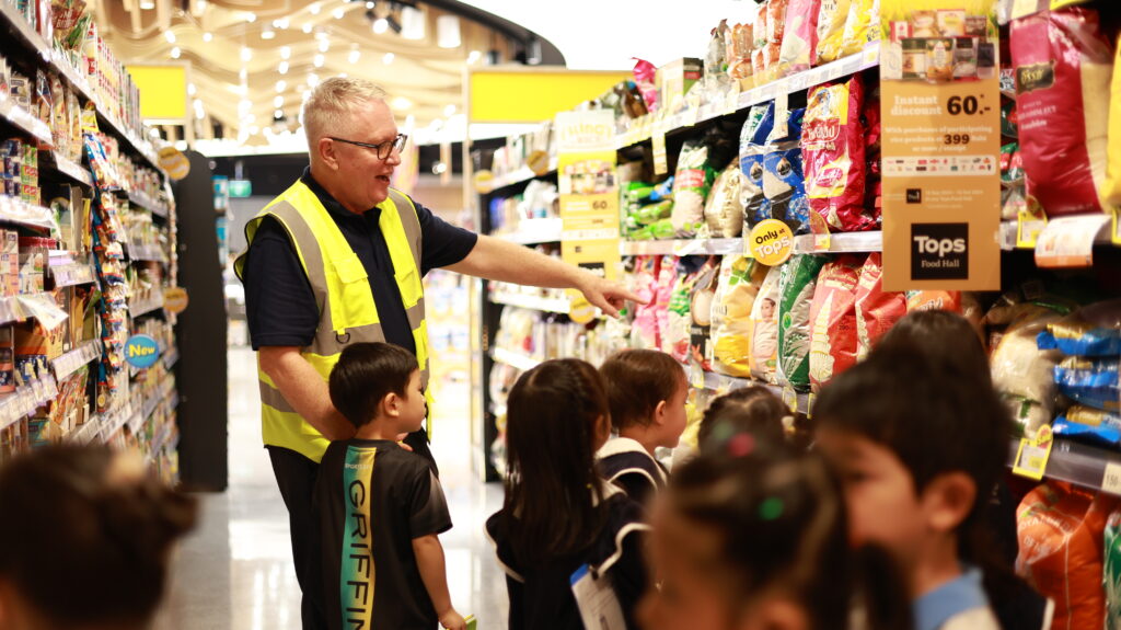 Mr. Chip teaching his students about the different products sold at a supermarket.